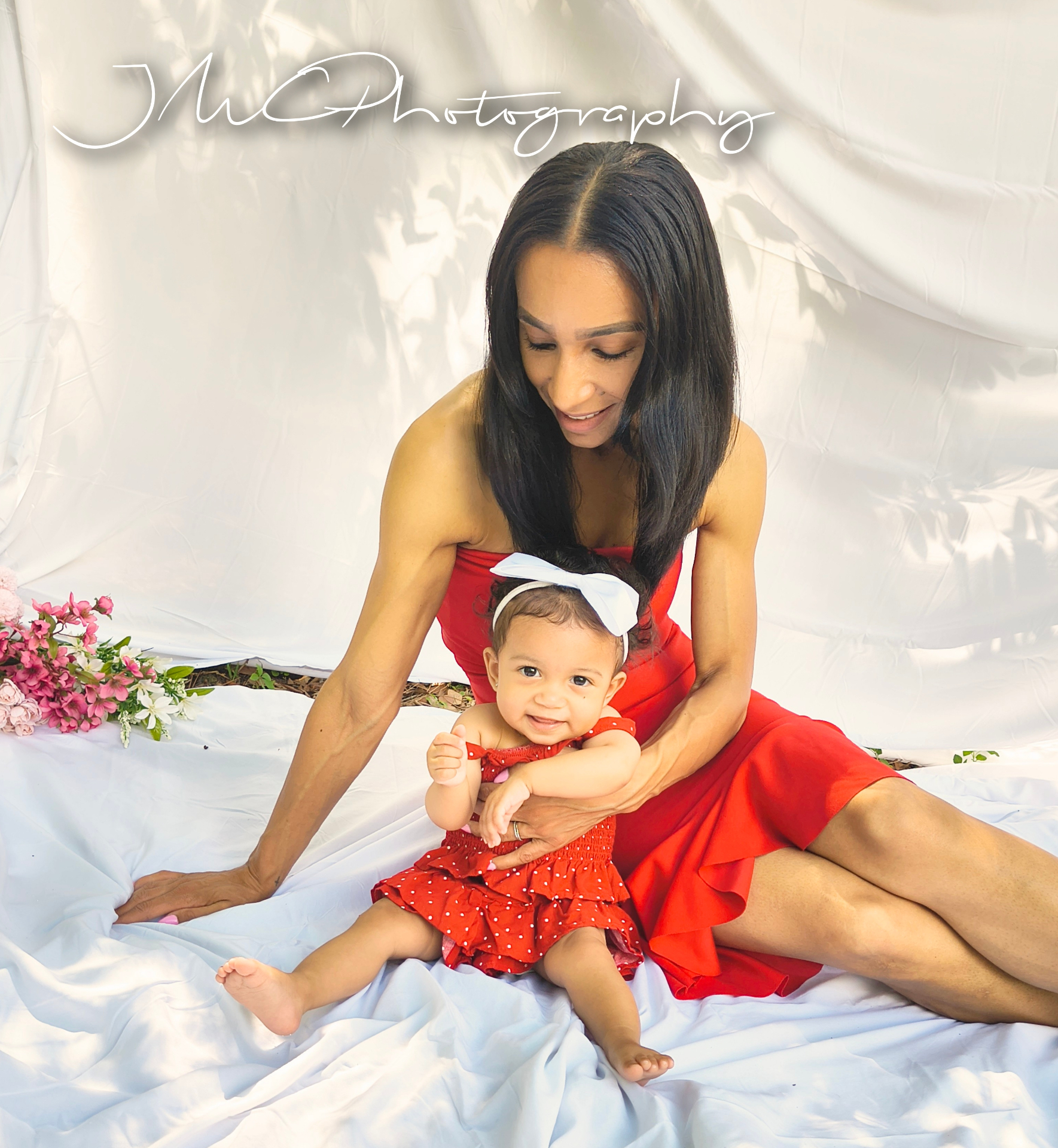 Mother and baby girl in matching red on white backdrop