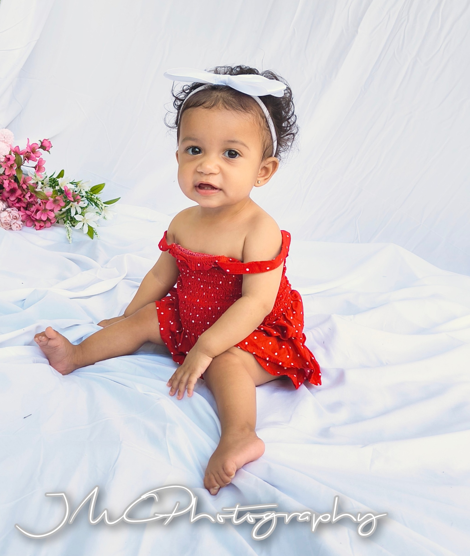 Baby girl in red polka-dot dress with white bow