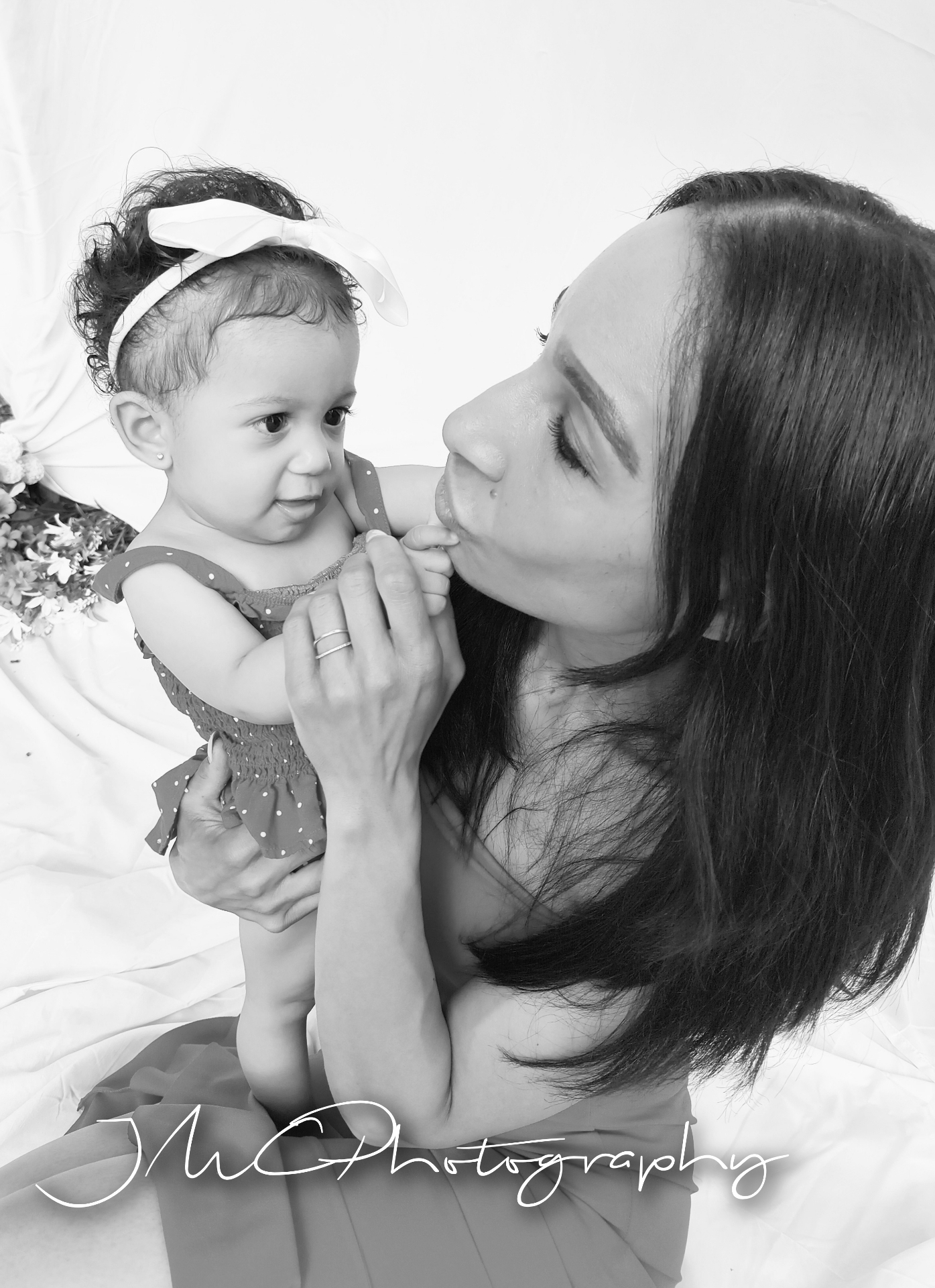 Black and white portrait of mother kissing baby daughter