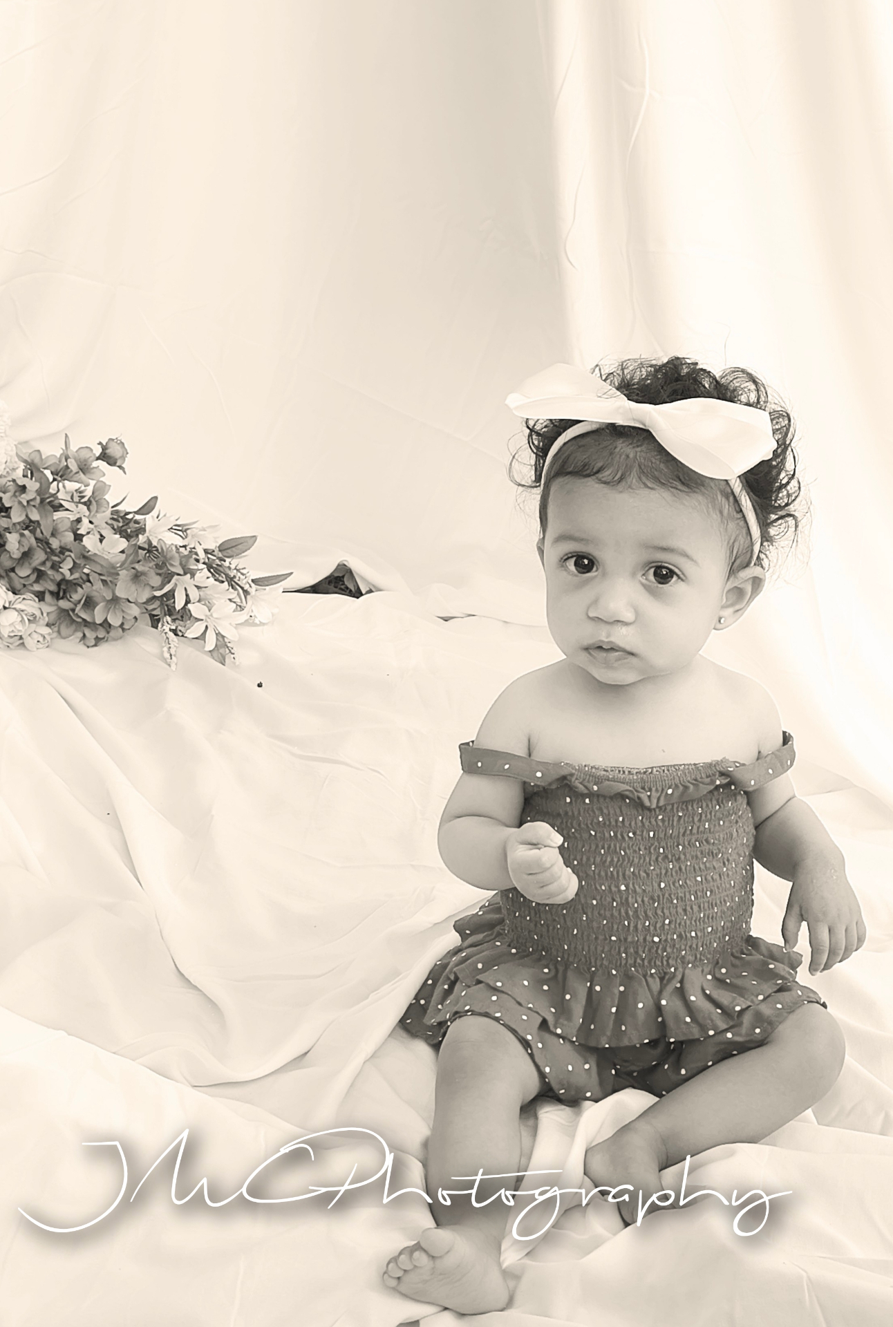 Soft monochrome portrait of baby girl with bow